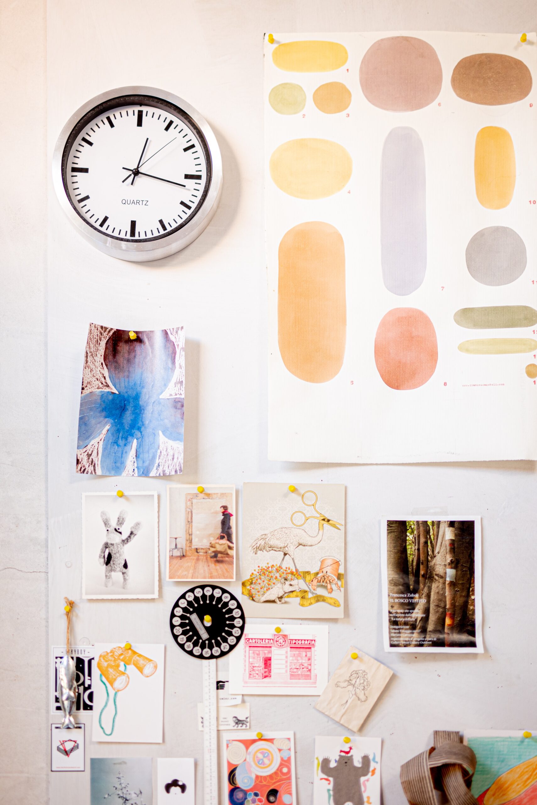 A wall with many pieces of art and a clock
