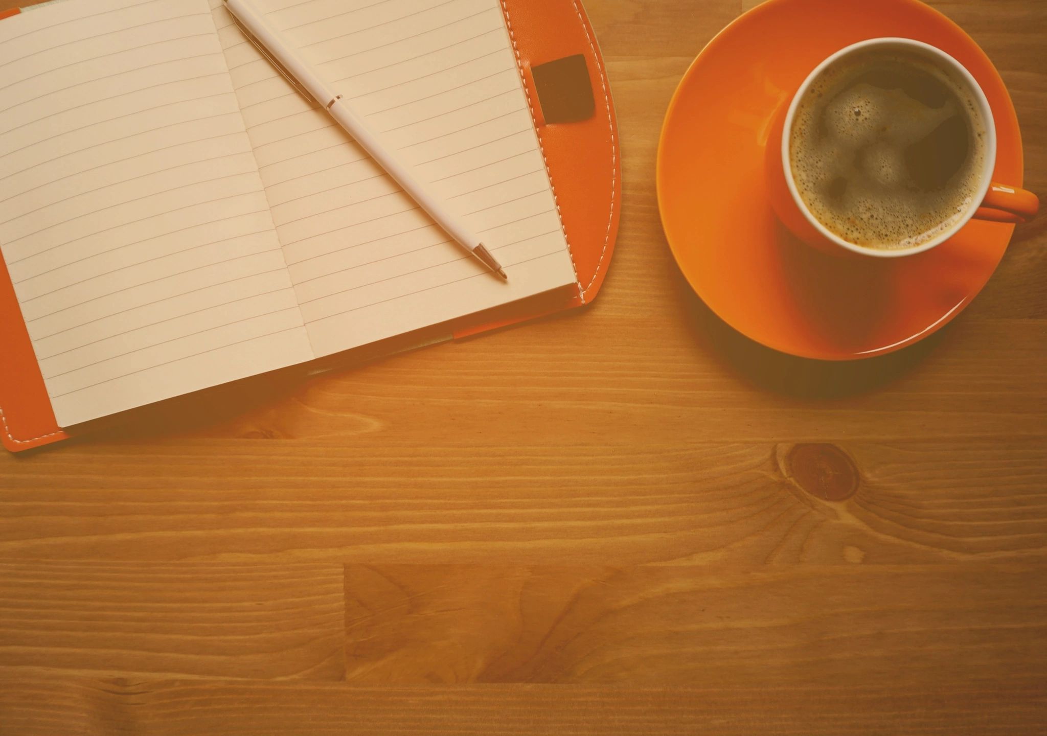 wooden table with coffee cup and open notebook with pencil
